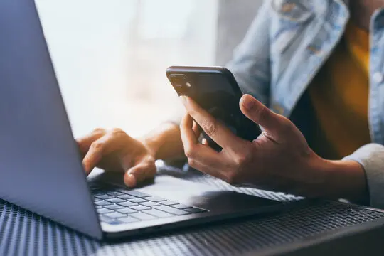 Person using laptop and smartphone